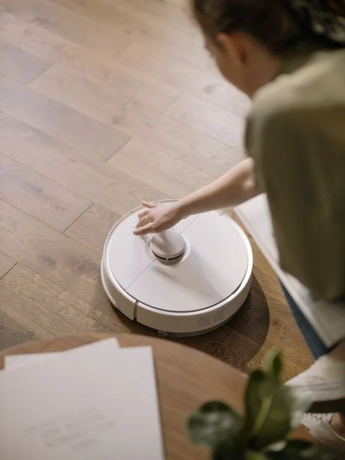 A joyful couple engages in a playful cleaning fight in their living room, showcasing light-hearted domestic life.